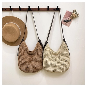 Detailed view of hand-woven straw shoulder bags in brown and beige colors with leather straps