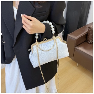 Detailed macro view of white floral jacquard fabric and pearl handle on shell bag