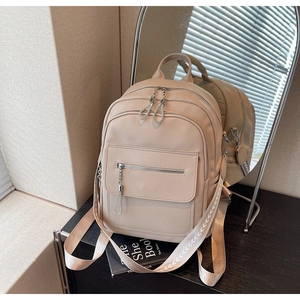 Detail of beige faux leather backpack showing multi-layer zippers and chain puller