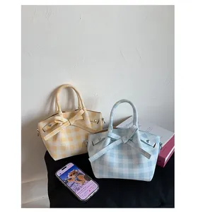 Détail de sacs à main à carreaux avec grands nœuds en bleu et jaune posés sur un tabouret