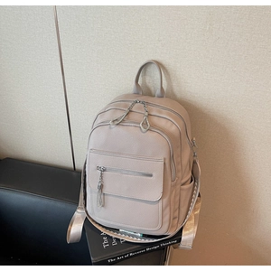 Close-up of the beige lychee pattern faux leather backpack on a black leather sofa