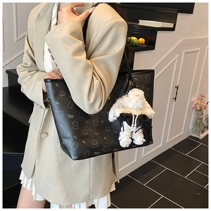 Detail of black tote bag featuring cartoon animal prints and a plush rabbit charm