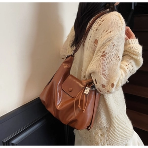Detail of brown leather tote bag with tassel charm and pocket on wooden stairs