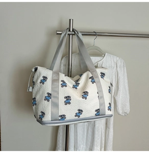 Close-up of quilted fabric travel bag with dog embroidery and expandable zipper bottom