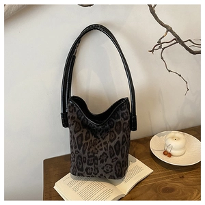 Detail of leopard print bucket bag on a wooden table with aesthetic home decor items