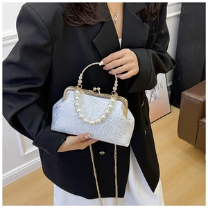 Detail of white jacquard shell bag with pearl strap and gold ring handle on a model
