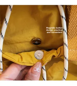 Gros plan du sac à dos en nylon jaune montrant la boucle magnétique et le cordon tressé