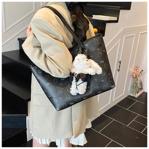 Detail of black printed tote bag with white bunny charm on a model's shoulder