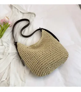 Detail of hand-woven straw shoulder bag with adjustable brown leather strap and metal buckle