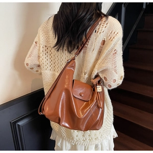 Brown hobo shoulder bag in glossy finish shown on model in a modern interior setting