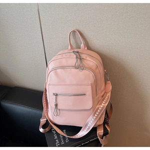 Detail of pink faux leather backpack featuring textured wide fabric strap and silver zippers