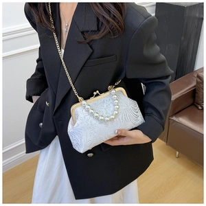 Detail of white floral embroidery bag with pearl handle and gold metal clasp on model