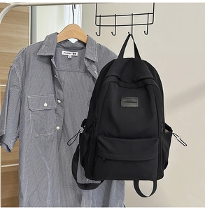 Detail of black water-resistant nylon backpack with drawstring side pockets on a metal rack