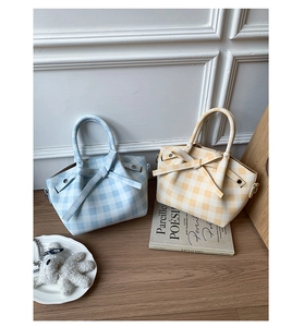 Détail de sacs à main à carreaux avec nœuds en bleu et jaune sur surface en bois