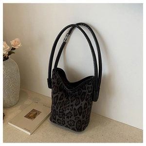 Detail of leopard print bucket bag with dual cylindrical handles on a stylish countertop