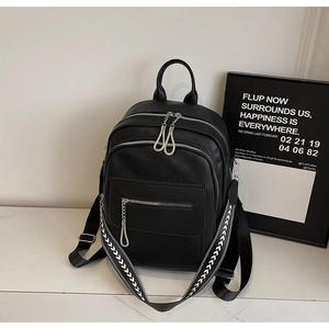 Detail of black leather backpack featuring stylish geometric patterned woven strap and zippers
