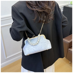 Detail of vintage white jacquard crossbody bag with phoenix pattern and pearl handle