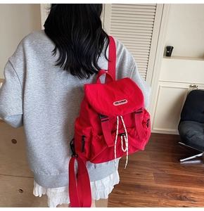 Macro detail of vibrant red backpack with adjustable drawstring and flap buckle closure