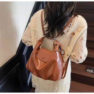 Detail view of caramel shiny leather backpack with T-shaped metal clasp on a model