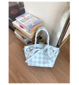Détail du sac à main à carreaux bleus avec un grand nœud décoratif et deux poignées