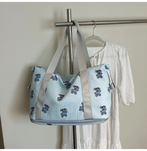 Detail of light blue quilted travel bag with cartoon puppy print and bottom shoe compartment