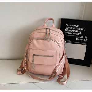 Detail of pink faux leather backpack featuring white V-weave straps and multiple zippers