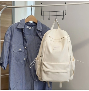 Detail of cream white minimalist travel backpack hanging with multiple side pockets