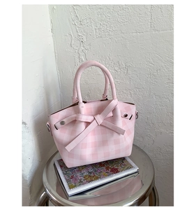 Détail du sac à main à carreaux rose avec grand nœud et rivets métalliques décoratifs