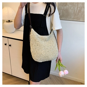 Straw shoulder bag with brown leather strap shown in a minimalist lifestyle setting