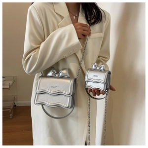 Close-up of silver bow chain bags with wavy edges in large and mini sizes