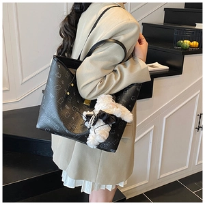 Detail of black pebbled leather tote bag with cartoon bear print and plush charm