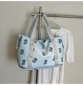 Detail of light blue quilted travel bag with teddy bear prints and bottom shoe compartment