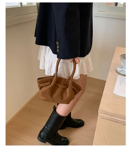 Detailed close-up of brown suede tote bag with stylish pleated wavy texture and thin straps