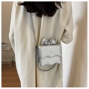 Close-up of a silver bow mini square bag with KCMK logo and elegant chain strap details