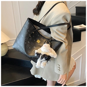 Close-up of black tote bag with white bear print and fluffy bunny charm decoration