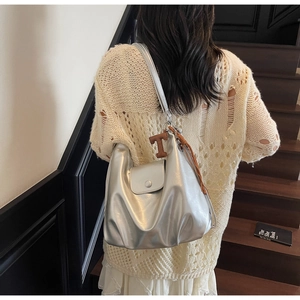 Detail of silver metallic hobo bag with a pleated design and brown leather T-pendant