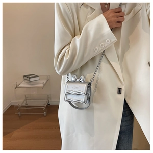 Detail of silver mini chain bag featuring a 3D bow and elegant wavy flap edge
