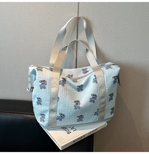 Macro detail of light blue seersucker travel bag with cute cartoon bear print and handles