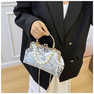 Detail of white jacquard shell bag with pearl chain and vintage golden metal frame