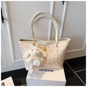 Detail of cream leather tote bag with cartoon bear print and plush bunny keychain charm