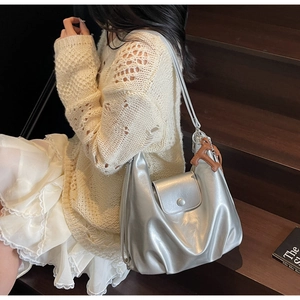 Silver metallic tote bag with charm accessory shown in a stylish fashion lifestyle scene