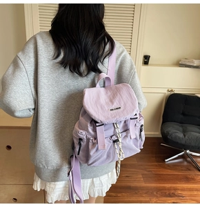 Detail of light purple nylon backpack showing drawstring closure and flap on woman's back