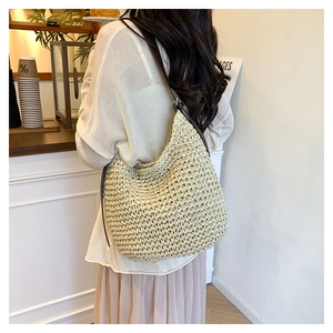 Close-up of beige woven straw tote with brown leather strap in a minimalist cafe setting