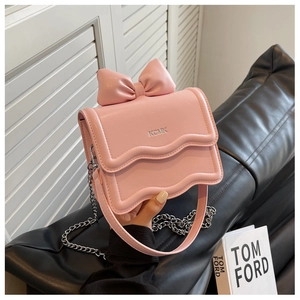 Close-up of pink bow mini bag featuring wave edge flap and silver chain strap