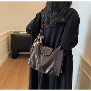 Detail view of coffee brown glossy PU leather tote bag with flap closure and decorative tassel