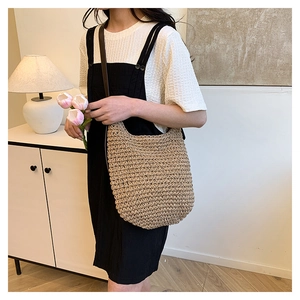 Straw hobo bag with leather strap shown in a cozy home setting with tulips