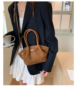 Detail of vintage brown suede tote bag with leather straps on a model in black blazer