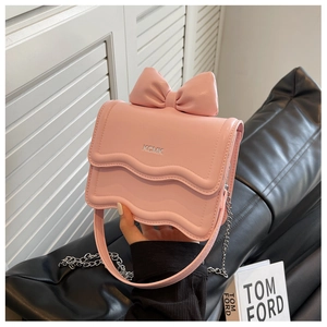 Detail of pink mini bag featuring bow decoration and scalloped edge with metal chain