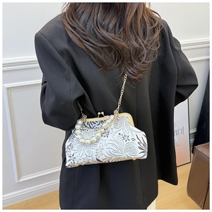 Detail view of floral shell bag with pearl handle and golden chain on model