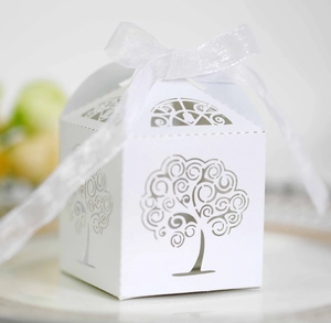 Detail of laser-cut tree pattern on white wedding favor box with silk ribbon